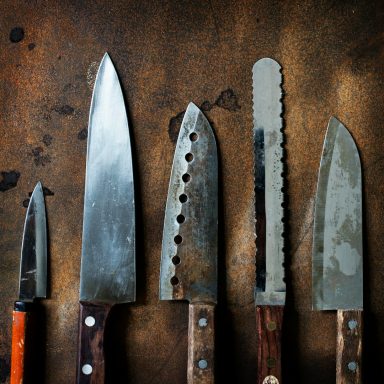 Assorted kitchen knives arranged on a rustic metal surface.
